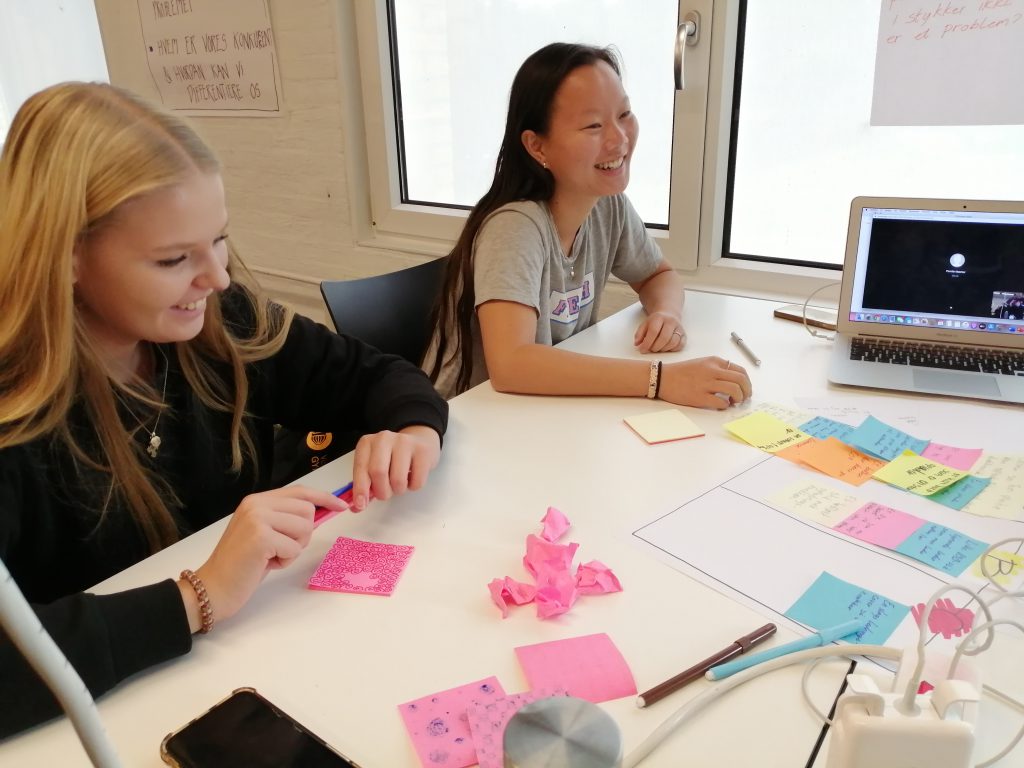 To elever sidder ved et bord og laver gruppearbejde og får ideer til innovation med masser af post-its.