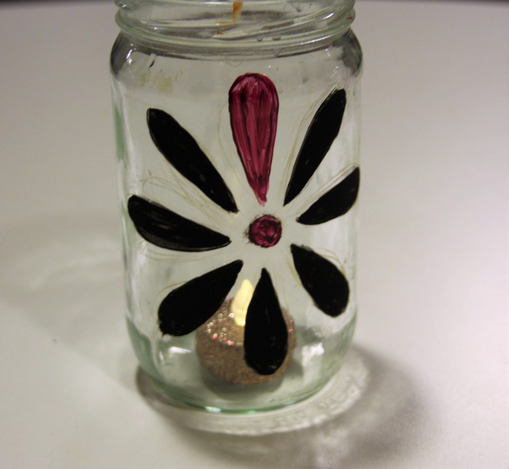 Marmeladeglas lavet om til fyrfadsstage pyntet med Knæk Cancer-blomsten.
