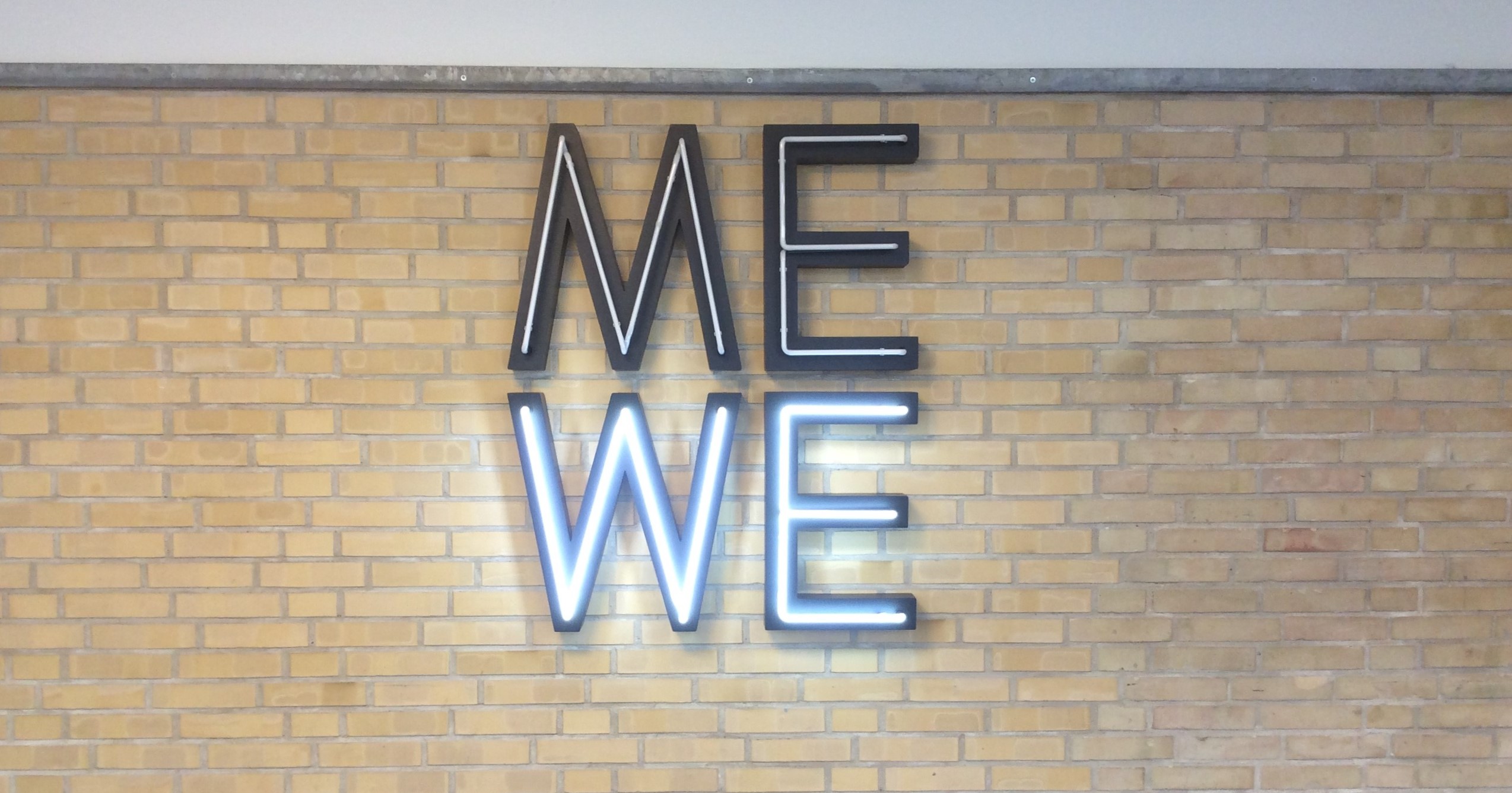 Gymnasiet. Kunst på 1. sal med bogstaverne ME - WE i neon.