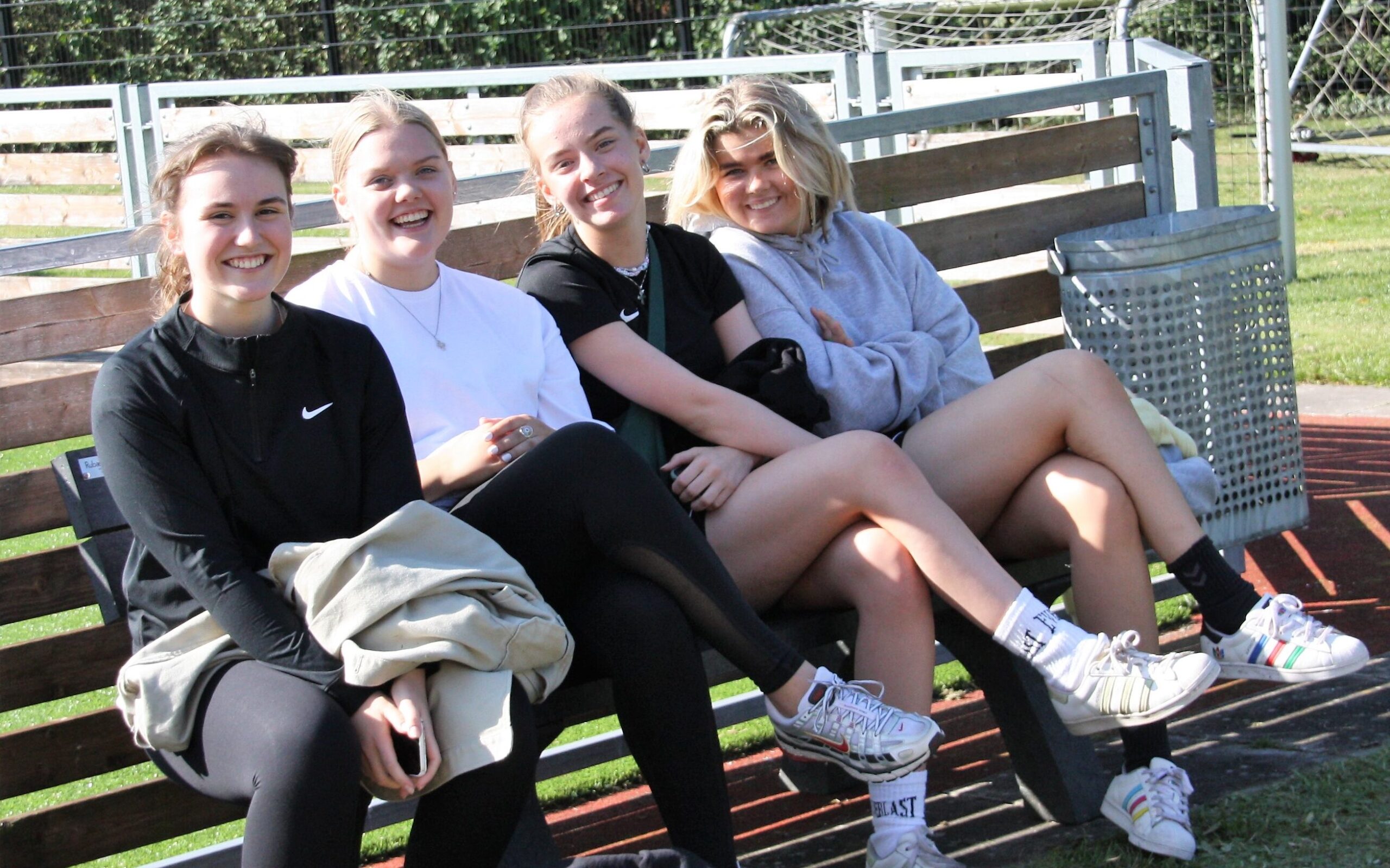 Aktivitetsdag 2021. Fire piger sidder og nyder solen ved fodboldbanen.