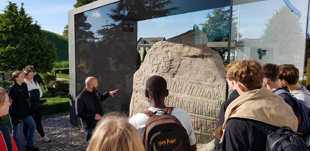 Jellineganlægget som huser Jelligestenen. Arkæolog fortæller eleverne om stenens betydning.