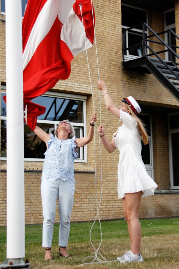 Årets første student Kathrine hejser flaget sammen med rektor.